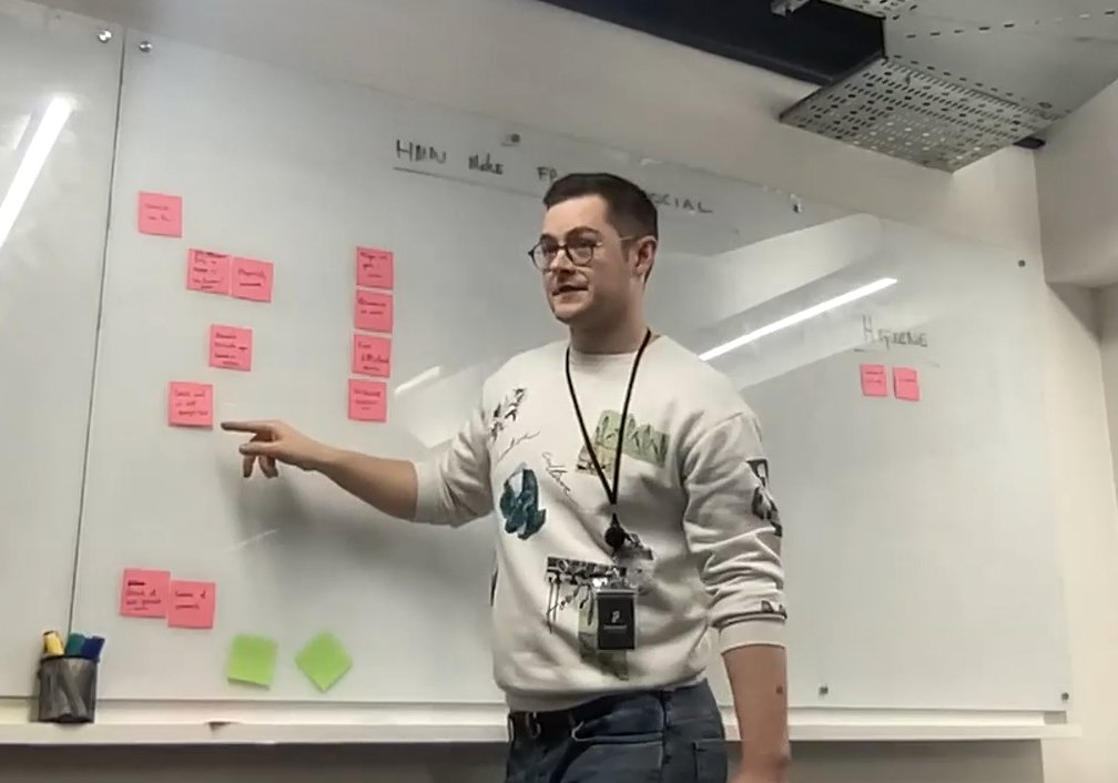 John presenting in front of a wall of pink sticky notes.