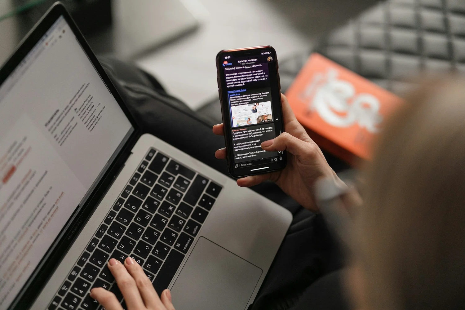 A phone and a laptop on an orange background, suggesting newsletter reading and podcast listening.
